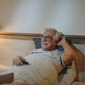 happy-senior-man-watching-tv-while-relaxing-bed-evening (1) (1)