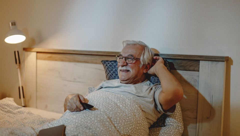 happy-senior-man-watching-tv-while-relaxing-bed-evening (1) (1)