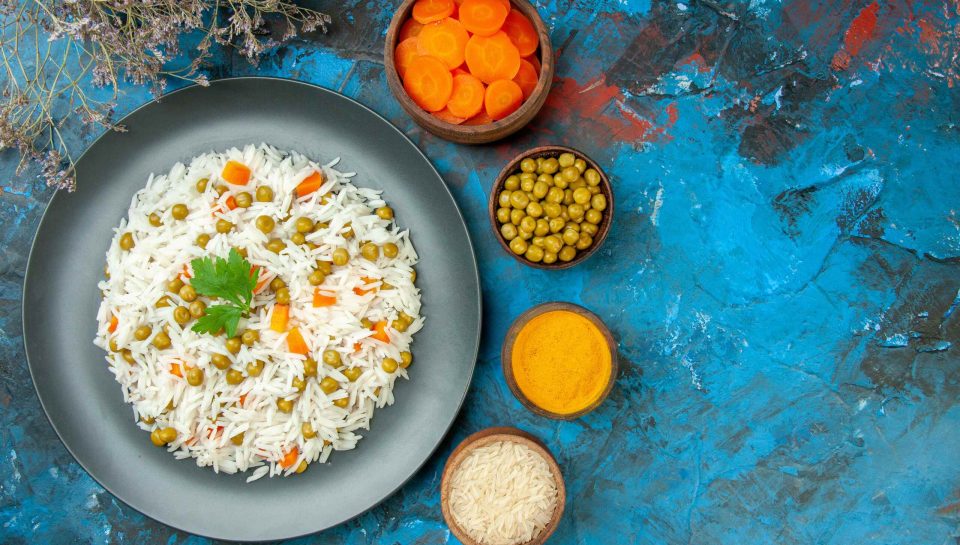 view-tasty-rice-meal-dinner-with-pisum-carrot-purple-stripped-towel-its-ingredients-blue-table (1) (1)